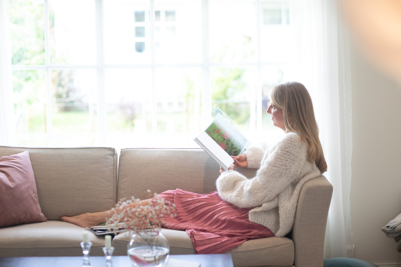 Sliten mamma tar en rolig pause for seg selv i sofaen ved vinduet